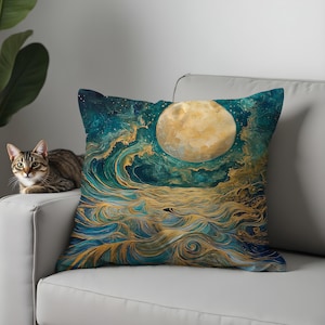 Puede incluir: Cojín cuadrado decorativo con una escena oceánica artística bajo la luna llena. El diseño presenta olas arremolinadas turquesas y doradas bajo una gran luna dorada. El cojín está sobre un sofá blanco, con un gato en el fondo.