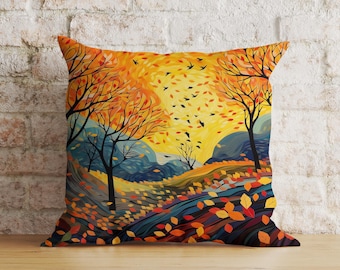 Puede incluir: Una almohada con una escena de otoño colorida con árboles, hojas y pájaros. El fondo es un degradado amarillo y naranja con un paisaje azul y verde en primer plano.