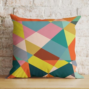 May include: A colourful geometric pattern cushion with a mix of orange, yellow, green, blue, pink, and brown colours. The cushion is made of a soft, comfortable fabric and is perfect for adding a pop of colour to any room.