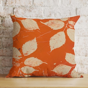 May include: Orange cushion with a white leaf pattern. The cushion is made of a soft, comfortable fabric and has a zip closure.