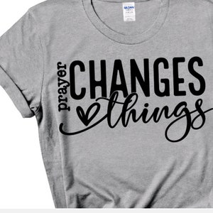 May include: Gray t-shirt with black text that reads "prayer changes things" with a heart symbol between the words.