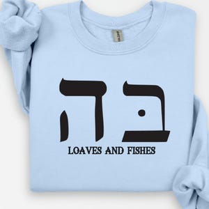 May include: Light blue sweatshirt with a black Hebrew symbol and the text "Loaves and Fishes".