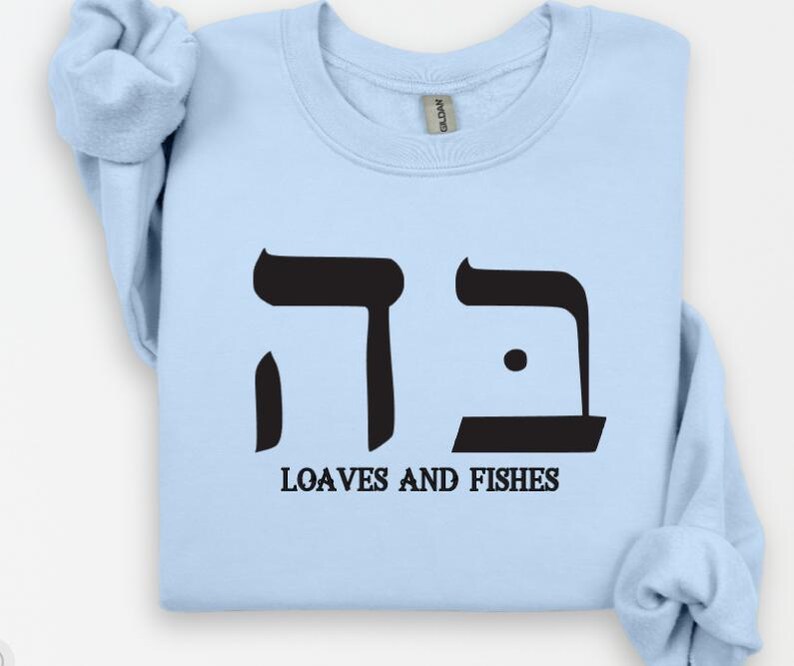 May include: Light blue sweatshirt with a black Hebrew symbol and the text "Loaves and Fishes".