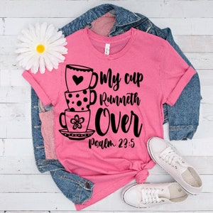 May include: Pink t-shirt with a black graphic of stacked teacups and the text "My cup runneth over Psalm 23:5".