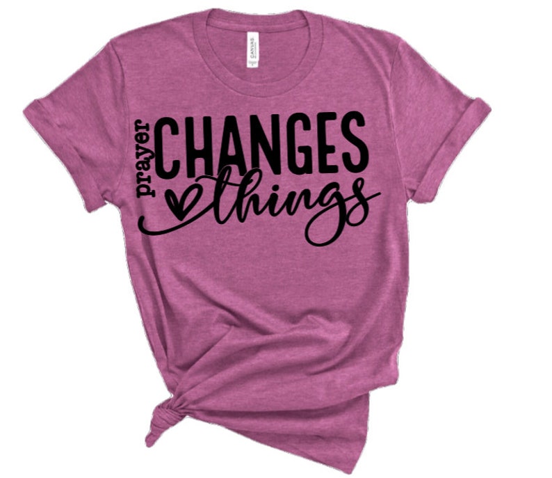 May include: A pink t-shirt with the text "prayer changes things" in black lettering with a heart symbol.