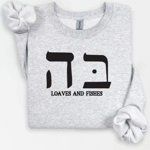 May include: A gray sweatshirt with the Hebrew word for "bread" and the words "Loaves and Fishes" printed in black.