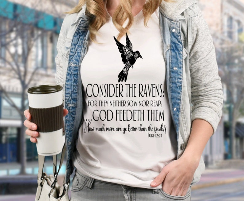May include: White t-shirt with a black silhouette of a bird with flowers and the text "CONSIDER THE RAVENS: FOR THEY NEITHER SOW NOR REAP: ...GOD FEEDETH THEM How much more are ye better than the fowls? LUKE 12:23"