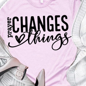 May include: Pink t-shirt with the text "prayer changes things" in black lettering with a small heart symbol.