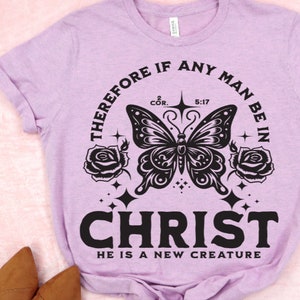 May include: A purple t-shirt with a black butterfly graphic and the text "THEREFORE IF ANY MAN BE IN CHRIST HE IS A NEW CREATURE" with the bible verse 2 COR. 5:17.