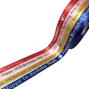 May include: A selection of satin ribbons in shades of red, pink, gold, and navy. Each ribbon is printed with celebratory messages like "Merry Christmas," "Happy 18th Birthday," and "Happy 50th Anniversary," alongside names. Suitable for gift wrapping and craft projects.