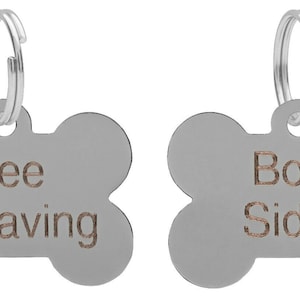 May include: Two silver bone-shaped dog tags with a silver ring. The tag on the left says "Free Engraving". The tag on the right says "Both Sides".