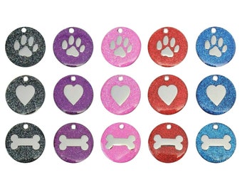May include: Assortment of 18 round pet ID tags with a glitter finish.  Tags feature paw print, heart, and bone designs in various colours including black, purple, pink, red, and blue.