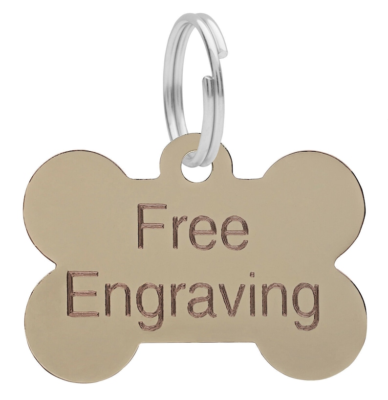 May include: Gold bone-shaped dog tag with a silver ring. The tag says "Free Engraving" in a brown font.