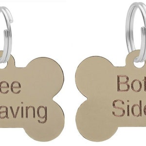 May include: Two gold bone-shaped dog tags with silver rings. The tag on the left says "Free Engraving". The tag on the right says "Both Sides".