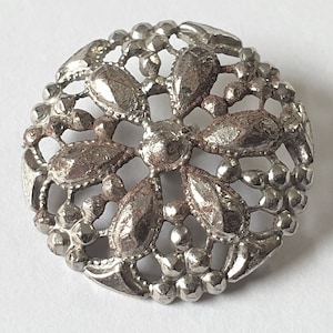 Pierced filigree domed white metal button with flower design. Circa 1880s and a loop shank. 13/16 inch or 20 mm. MB288