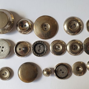 17 silver coloured buttons. Mix of celluloid and non magnetic metal. 1900s to 1950s.  Suitable for craft. Various sizes and shapes. MB308