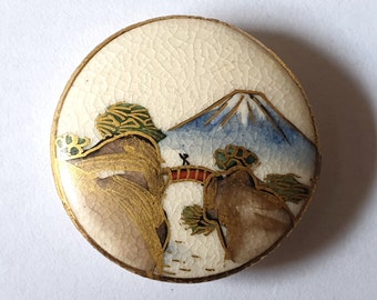 1 Japanese Satsuma ceramic button featuring a red bridge between two hills. Mount Fuji in the distance. 20th Century. 1" or 25.5mm. Sat7042