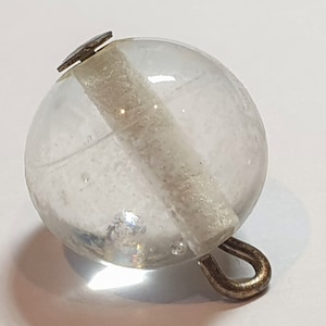 不透明ガラス製のペーパーウェイトボタン。内側に白いチューブと白い金属製のループシャンクが付いています。1900年代頃。直径1/2インチ（12mm）。PW739