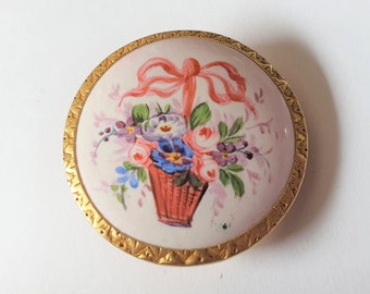 1 1880s large white enamel button set in brass and featuring a basket of flowers. Flowing pink ribbon. Loop shank. 1 3/16" or 31mm. EB6197