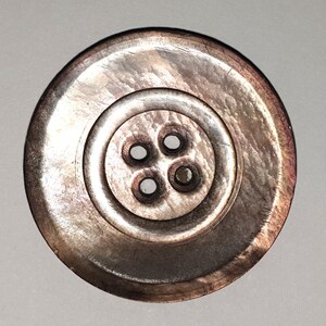 中央下部に 4 つの縫い穴がある大きなマザー オブ パール ボタン。1 3/16 インチまたは 30 mm。NM267