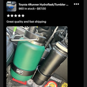 May include: A green and black insulated water bottle with a handle, and a black insulated water bottle, both in a car cup holder. The green bottle has a black band with the word "PEN" on it. The black bottle has a black band with the words "HANDMADESHIFTS" on it.