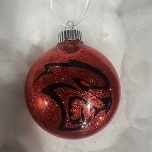 May include: Red glitter Christmas ornament with a black and red Dodge Challenger logo.