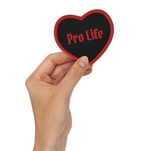 May include: A red heart-shaped patch with a black center and the words "Pro Life" embroidered in red.