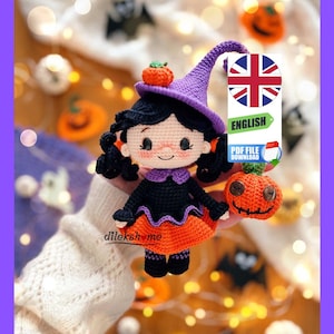 Pode incluir: Boneca bruxa amigurumi de crochê usando um chapéu roxo e um vestido laranja segurando uma abóbora. A boneca tem cabelo preto e um rosto sorridente. A boneca está cercada por um fundo desfocado de abóboras laranja e luzes.