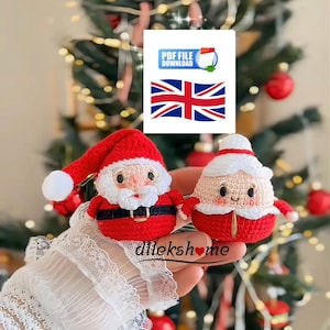 以下が含まれることがあります： サンタクロースとミセス・クロースの形をした、2つのかぎ針編みのクリスマスオーナメント。サンタのオーナメントは赤い帽子と黒いベルトのスーツを着ています。ミセス・クロースのオーナメントは白い帽子と赤いドレスを着ています。PDFファイルダウンロードグラフィックとユニオンジャックの旗が背景にあります。