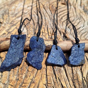 May include: Four blue stone pendants on black cords. The stones are irregularly shaped and have a rough, textured surface.