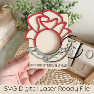 May include: A wooden cutout of a red rose with a blank circle in the center. The text "You've planted yourself in my heart" is written below the rose.