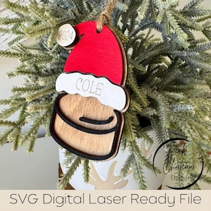 May include: A wooden Christmas bauble shaped like a Santa hat with a red hat, white trim, and a black outline. The bauble has the name "COLE" written on the front and a small wooden circle with the year "2024" on the top.