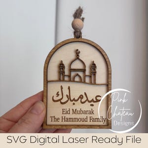 Peut inclure: Ornement en bois Eid Mubarak avec une silhouette de mosquée, une écriture arabe et du texte en anglais. L'ornement est découpé au laser avec une finition en bois naturel, avec un dessus décoratif avec une perle en bois et de la ficelle pour l'accrocher. Le texte comprend "Eid Mubarak".