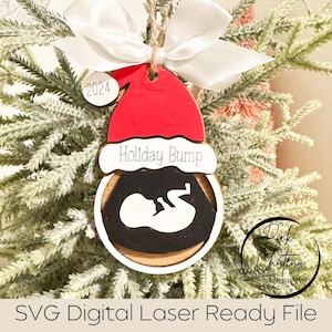 May include: A wooden Christmas bauble shaped like a Santa hat with a black and white ultrasound image inside. The bauble says "Holiday Bump" and has the year "2024" on it.