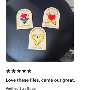 May include: Three wooden Valentine's Day decorations. One features a heart and flowers, another a pencil and heart, and the third a heart-shaped pencil. Each has a message: "You Make My Heart Bloom," "You're the WRITE Number for Me," and "Teaching Little Hearts & Big Minds."