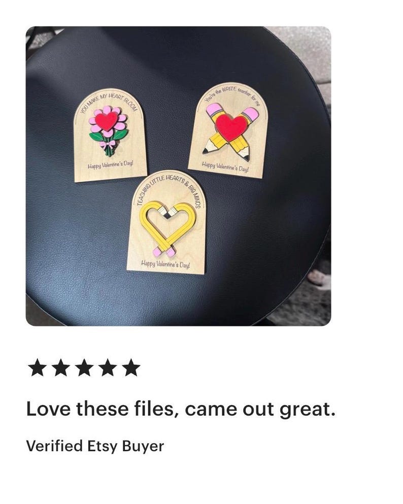 May include: Three wooden Valentine's Day decorations. One features a heart and flowers, another a pencil and heart, and the third a heart-shaped pencil. Each has a message: "You Make My Heart Bloom," "You're the WRITE Number for Me," and "Teaching Little Hearts & Big Minds."