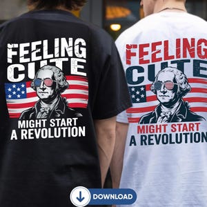 May include: A black t-shirt and a white t-shirt, each featuring a graphic of George Washington wearing sunglasses with an American flag pattern. The design includes the text "FEELING CUTE" and "MIGHT START A REVOLUTION" over a waving American flag.