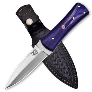 May include: A purple and black knife with a leather sheath. The knife has a double-edged blade and a wooden handle with a red and gold emblem.