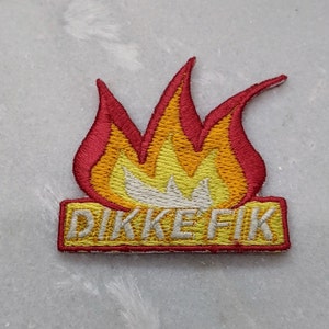 Op de afbeelding: Geborduurde patch met een vlamontwerp in rood, oranje en geel. De patch heeft de tekst "DIKKE FIK" in gele letters op een rechthoekige achtergrond.