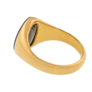 K&ouml;nnte beinhalten: Ein goldfarbener Ring mit einem dunkelgr&uuml;nen, oval geformten Stein. Der Ring hat eine glatte, polierte Oberfl&auml;che und ein klassisches Design. Der Stein ist b&uuml;ndig mit der Oberfl&auml;che des Rings eingesetzt.
