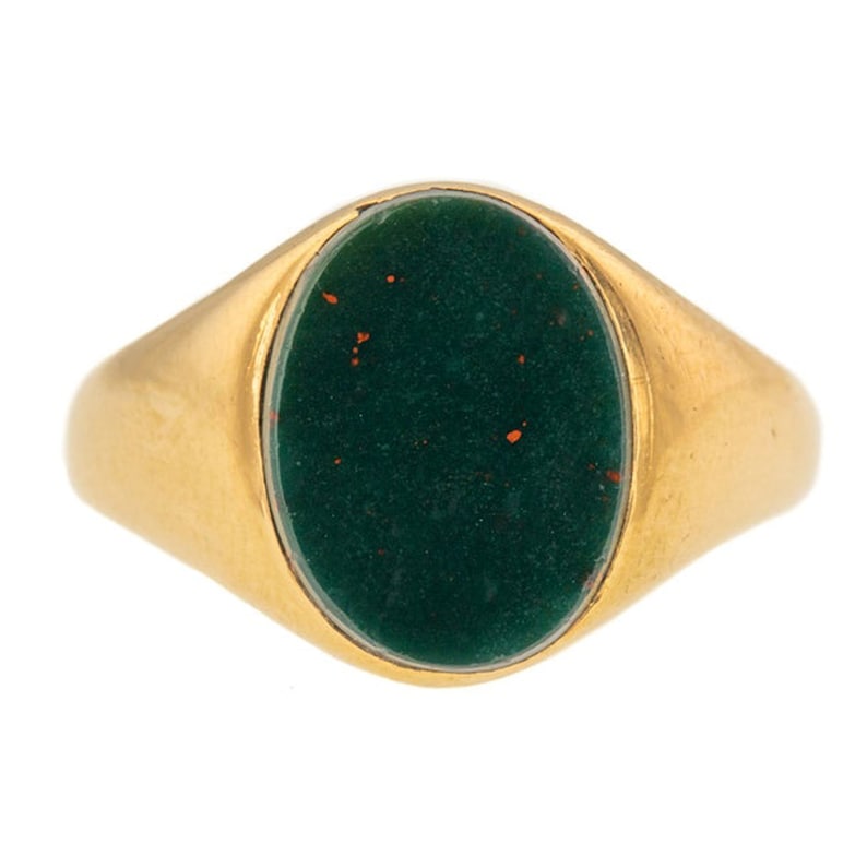 K&ouml;nnte beinhalten: Ein goldener Ring mit einem ovalen, dunkelgr&uuml;nen Stein. Der Stein hat kleine rote Flecken. Der Ring hat ein poliertes Goldband. Die Fassung ist b&uuml;ndig mit dem Band.