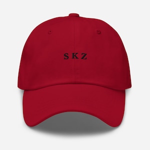 May include: A red baseball cap with the text "SKZ" embroidered in black on the front.