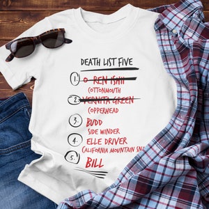Puede incluir: Camiseta blanca con un gráfico en negro y rojo que dice "Death List Five" con una lista de nombres y descripciones. Los nombres están tachados en rojo.