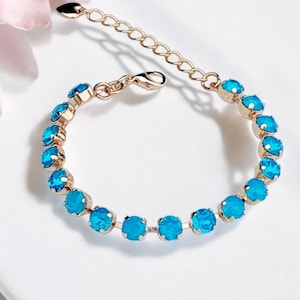 Może przedstawiać: Złota bransoletka z rzędem turkusowych kryształów.