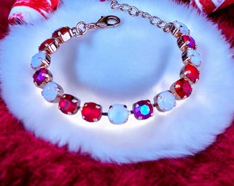 May include: A rose gold tone bracelet featuring alternating round faceted red and iridescent white crystals. The bracelet includes a lobster claw clasp and an adjustable chain link extension, showcasing a repeating pattern of vibrant red and white stones.