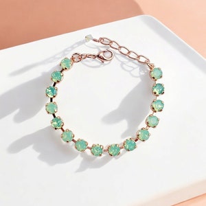 Pode incluir: Um bracelete delicado com uma corrente de ouro rosa e uma fila de pedras de opala verde claro.