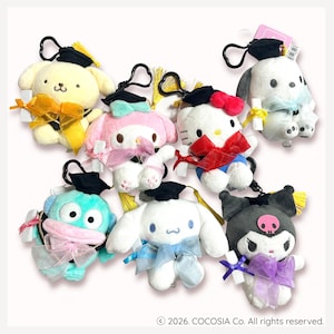 May include: A collection of plush character keychains, each wearing a graduation cap and bow. The characters include a yellow dog, a pink bunny, Hello Kitty, a white dog, a blue creature, a white bunny, and a black character with a skull.