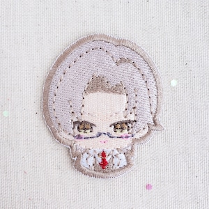 May include: Embroidered patch of a cartoon character with brown hair, wearing glasses and a red tie. The character has a light pink complexion and is wearing a white shirt.