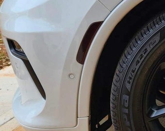 May include: Close-up of a white SUV with a black tire and wheel. The tire has the text "H/L 422 Plus" on the side.