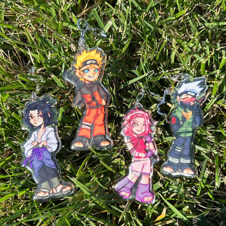 K&ouml;nnte beinhalten: Vier Acryl-Schl&uuml;sselanh&auml;nger mit Anime-Charakteren. Die Charaktere sind Naruto, Sasuke, Sakura und Kakashi. Jeder Schl&uuml;sselanh&auml;nger hat eine silberfarbene Kette und ein klares, gl&auml;nzendes Finish. Die Charaktere sind in leuchtenden Farben dargestellt.